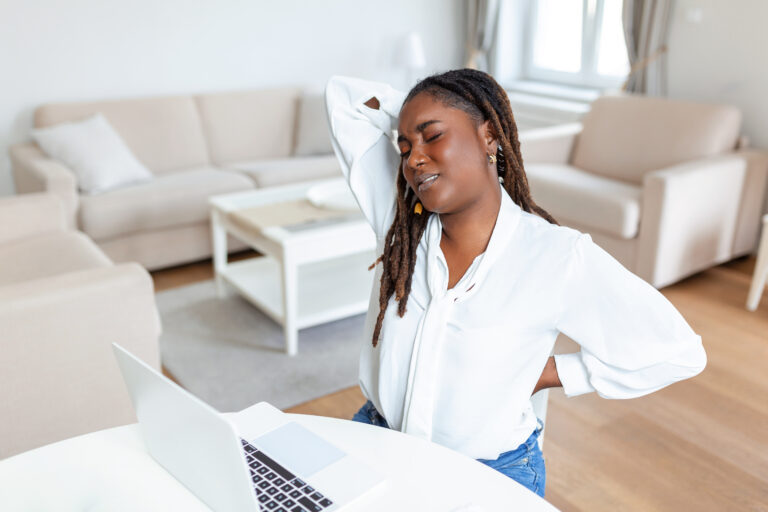 young african businesswoman having back pain while sitting office desk businesswoman holding her back while working laptop office desk